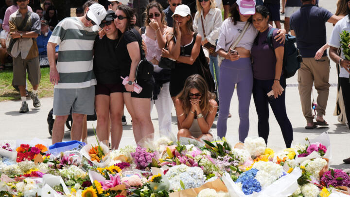 Des personnes se rassemblent devant des fleurs déposées en hommage aux victimes de la fusillade de Sydney, lundi 15 décembre 2025