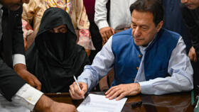 Pakistan's former Prime Minister Imran Khan (R), along with his wife Bushra Bibi (C), signs surety bonds for bail in various cases at a registrar office in the High Court, in Lahore, Pakistan.