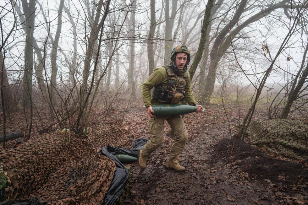 A Ukrainian soldier from the Da Vinci Wolves battalion carries an artillery shell to fire at Russian positions on the front line in eastern Ukraine.