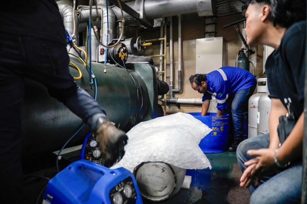 Des techniciens de la société Recoolit travaillent à capturer les gaz de refroidissement d'une grande unité de climatisation à Jakarta, le 10 juin 2025 en Indonésie.