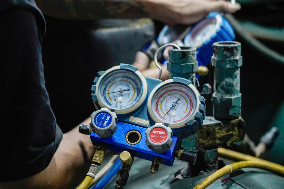 Des techniciens de la société Recoolit suivent sur des jauges le captage des gaz de refroidissement d'une grande unité de climatisation à Jakarta, le 10 juin 2025 en Indonésie.