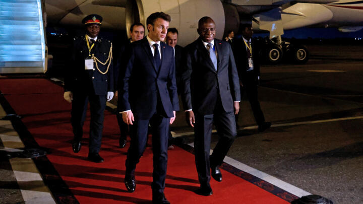 French President Emmanuel Macron is escorted by a government representative upon arrival at arrives at Luanda International Airport in Luanda, Angola early on March 3, 2023. - Macron arrived in the former Portuguese colony of Angola on March 3, where he is set to sign an accord to develop the agricultural sector as part of a drive to enhance French ties with anglophone and Portuguese-speaking Africa. (Photo by LUDOVIC MARIN / AFP)