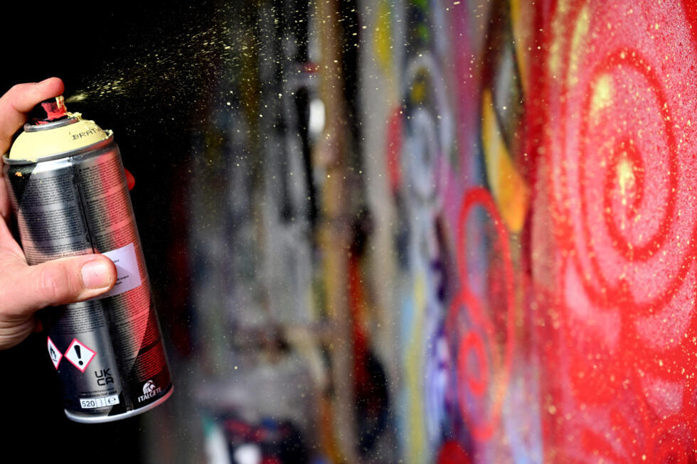 Le street artiste bosniaque Benjamin Cengic appose sa signature "Flower Graffitti" sur un mur de son espace de création, à Sarajevo, le 22 mai 2025.
