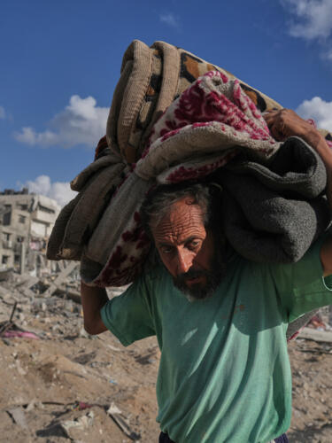 El palestino desplazado Muhammad Miqdad lleva sus pertenencias por la calle Al-Jalaa, gravemente dañada, en la ciudad de Gaza, el 12 de octubre de 2025.