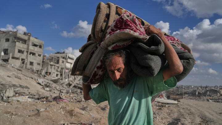 Displaced Palestinian Muhammad Miqdad carries his belongings along the heavily damaged Al-Jalaa street in Gaza City on October 12, 2025.