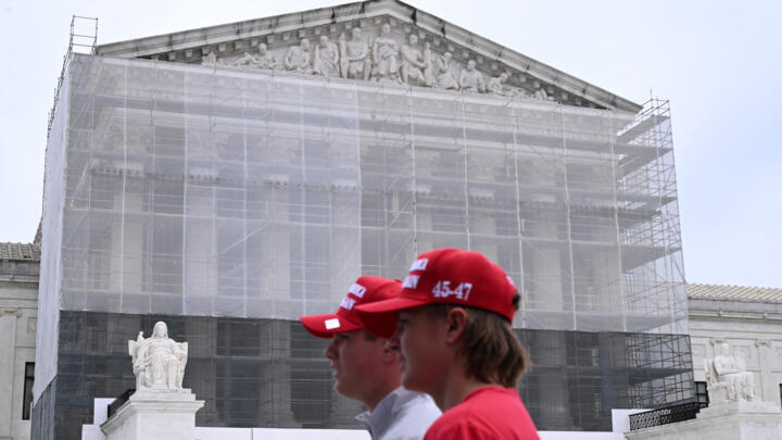 Two mean wearing "Make America Great Again Hats" walk by the Supreme Court in Washington, DC, on June 27, 2025.