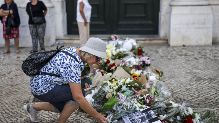 A woman places flowers next to other tributes displayed at the site of the Gloria funicular accident in Lisbon on September 5, 2025.