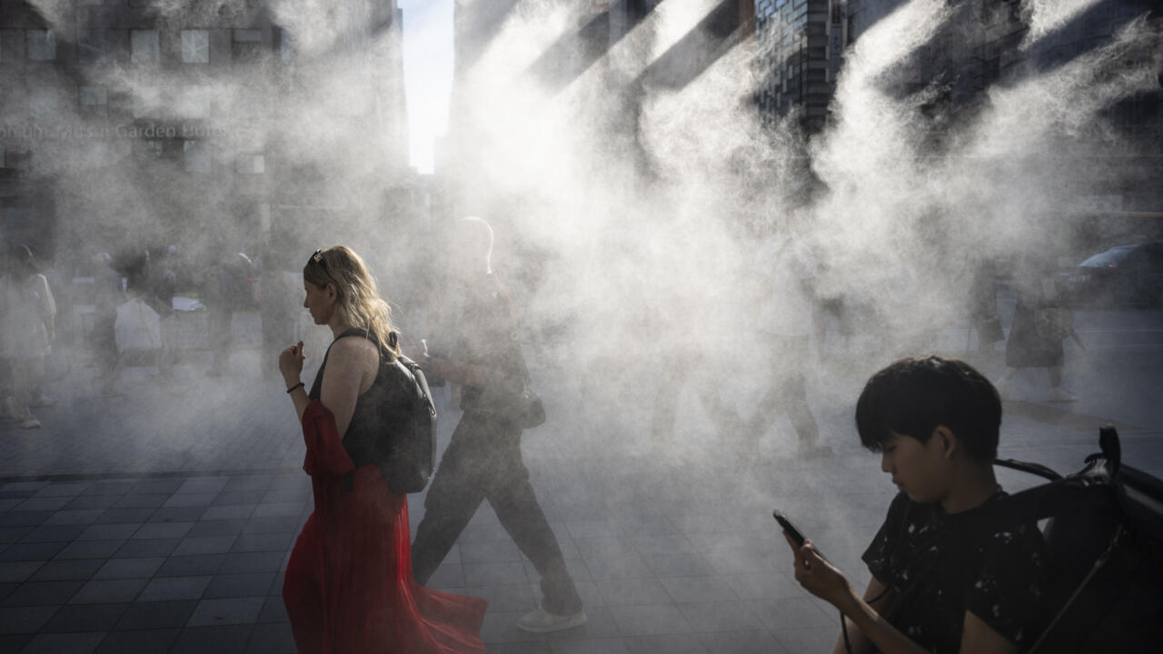 People walk under a misting system on a hot day in Tokyo earlier this year, which is on track to become one of the hottest in recorded history, according to the UN