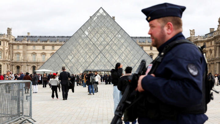  A French CRS riot police officer patrols near the glass Pyramid of the Louvre Museum, after French police arrested suspects in the Louvre heist case, in Paris, France, on October 27, 2025. 