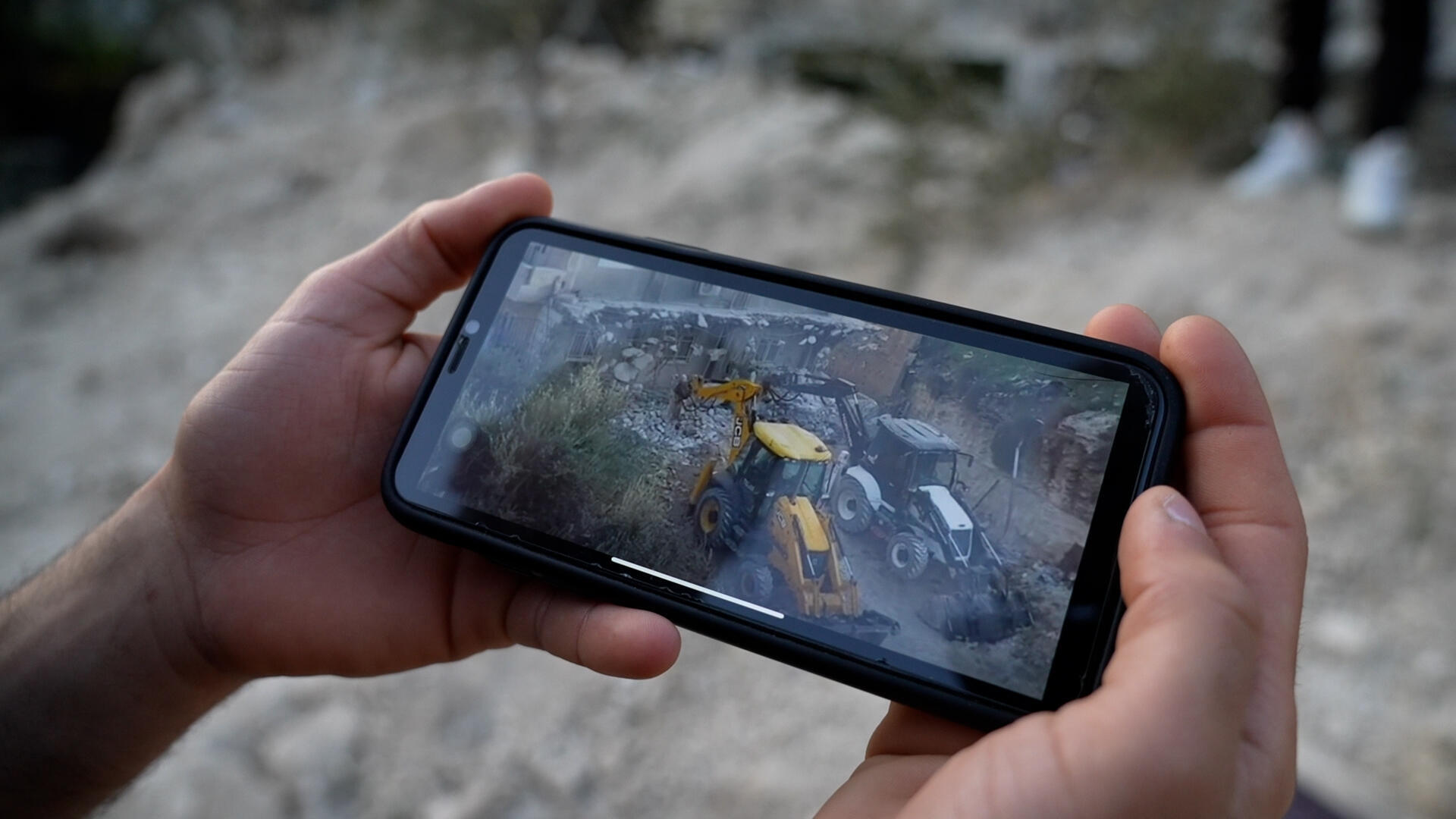 Zakariya muestra en su teléfono un video del momento en el que las excavadoras israelÃes remataron el derribo de su vivienda y maltrataron la edificación contigua de su familia.