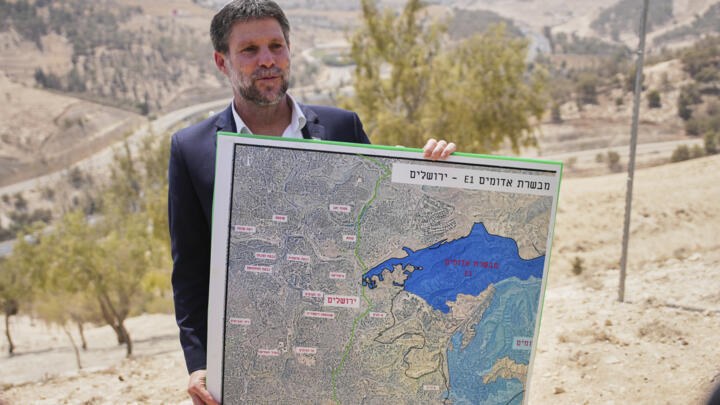 Israeli Finance Minister Bezalel Smotrich holds a map that shows the E1 settlement project during a press conference near the settlement of Maale Adumim in the West Bank on August 14, 2025.