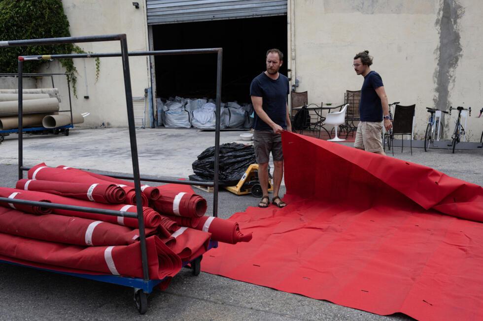 Cette photo prise à Marseille le 4 juin 2025 montre des recycleurs et des employés de l'association "La réserve des arts" récupérant  des tapis rouges utilisés lors du dernier Festival de Cannes