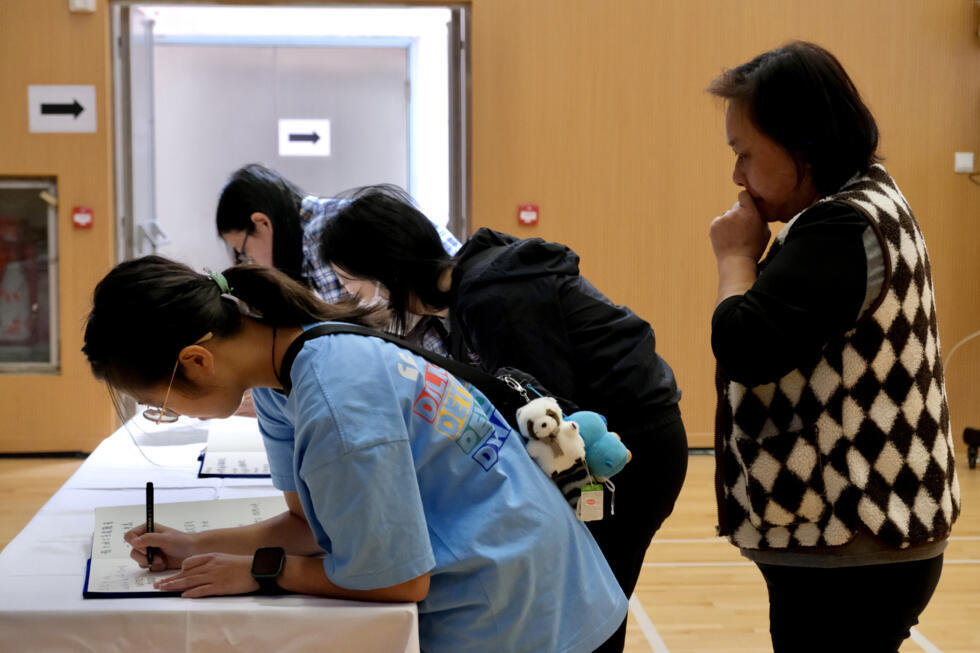 Mourners write in books as they pay their respects at a memorial point in Tai Po district.