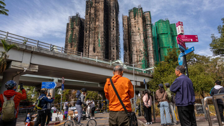 People look at the aftermath of a major fire that swept through several apartment blocks at the Wang Fuk Court residential estate