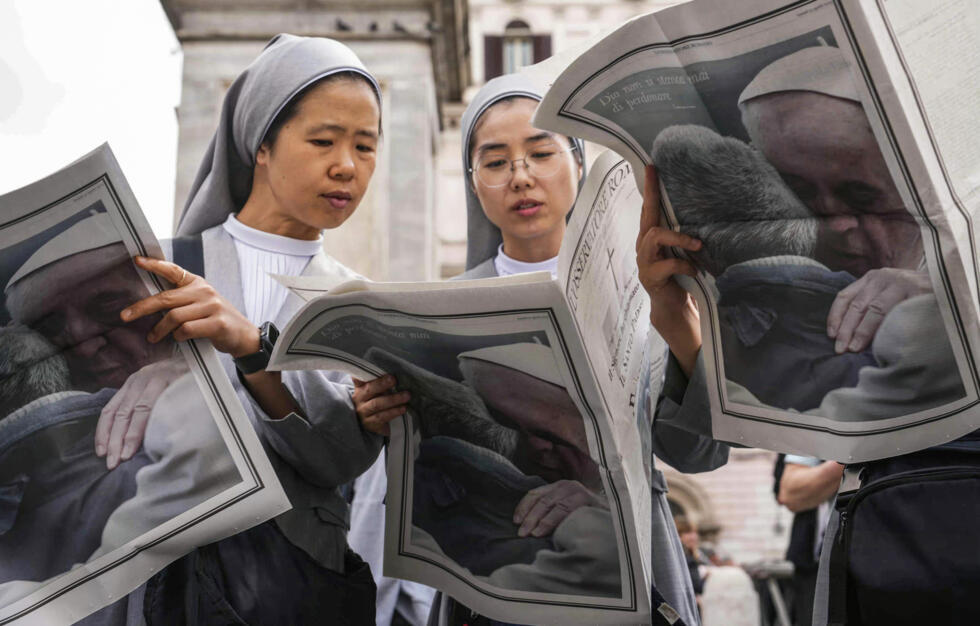 Des religieuses lisent le journal Osservatore Romano avec le pape François en dernière page près de la basilique Sainte-Marie-Majeure, un jour avant les funérailles du défunt pape, à Rome, le 25 avril 2025
