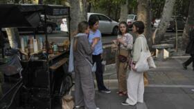 Iranian women drink coffee on a sidewalk in northern Tehran, on May 3, 2025. 