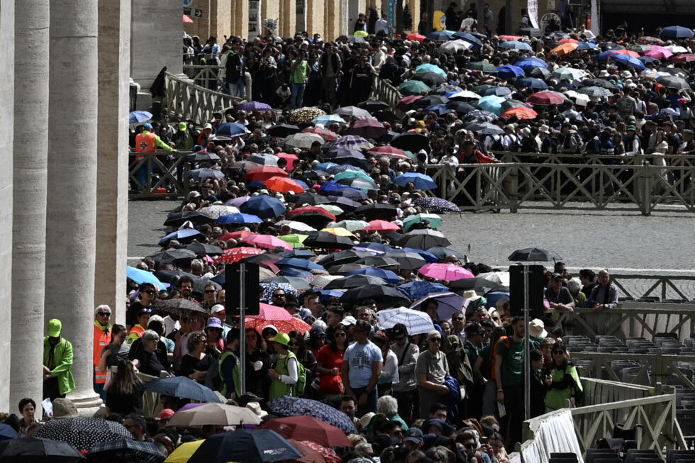 Les gens font la queue avec des parapluies sur la place Saint-Pierre pour accéder à la basilique où est exposé le corps du pape François, au Vatican, le 25 avril 2025