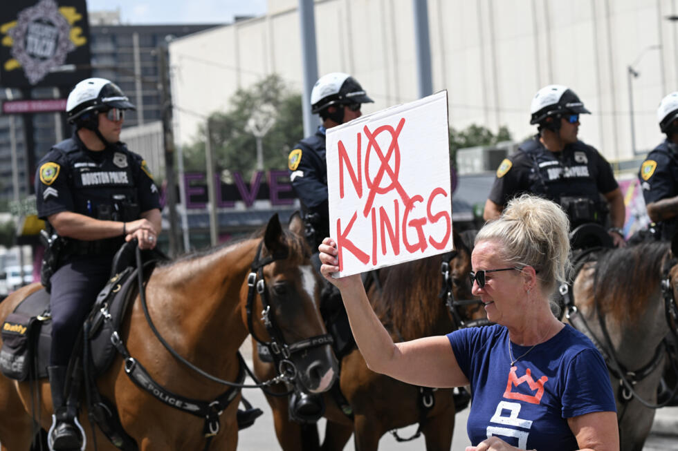A protester holds a 'No Kings' sign as police monitor a rally in Houston, Texas, on September 1, 2025