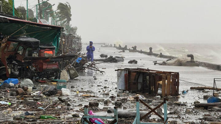 A man stands near debris on a waterfront road amid heavy rain driven by Super Typhoon Ragasa in the Philippines' Cagayan province on Monday, September 22, 2025.
