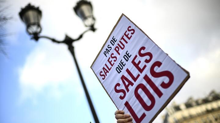 A protester holds a placard reading "no nasty whores, just nasty laws" during a demonstration called by sex workers on the International Day to End Violence Against Sex Workers in Paris on December 17