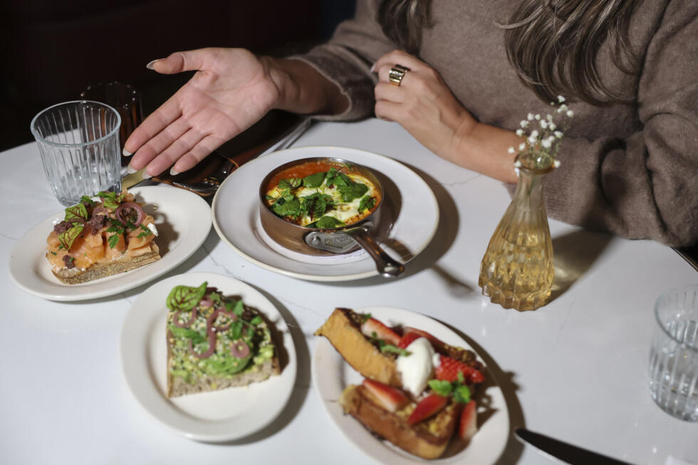 A patron poses at a table with an array of half-sized portions of meals that some restaurants are offering as more and more people have smaller appetites due to weight-loss drugs like Ozempic