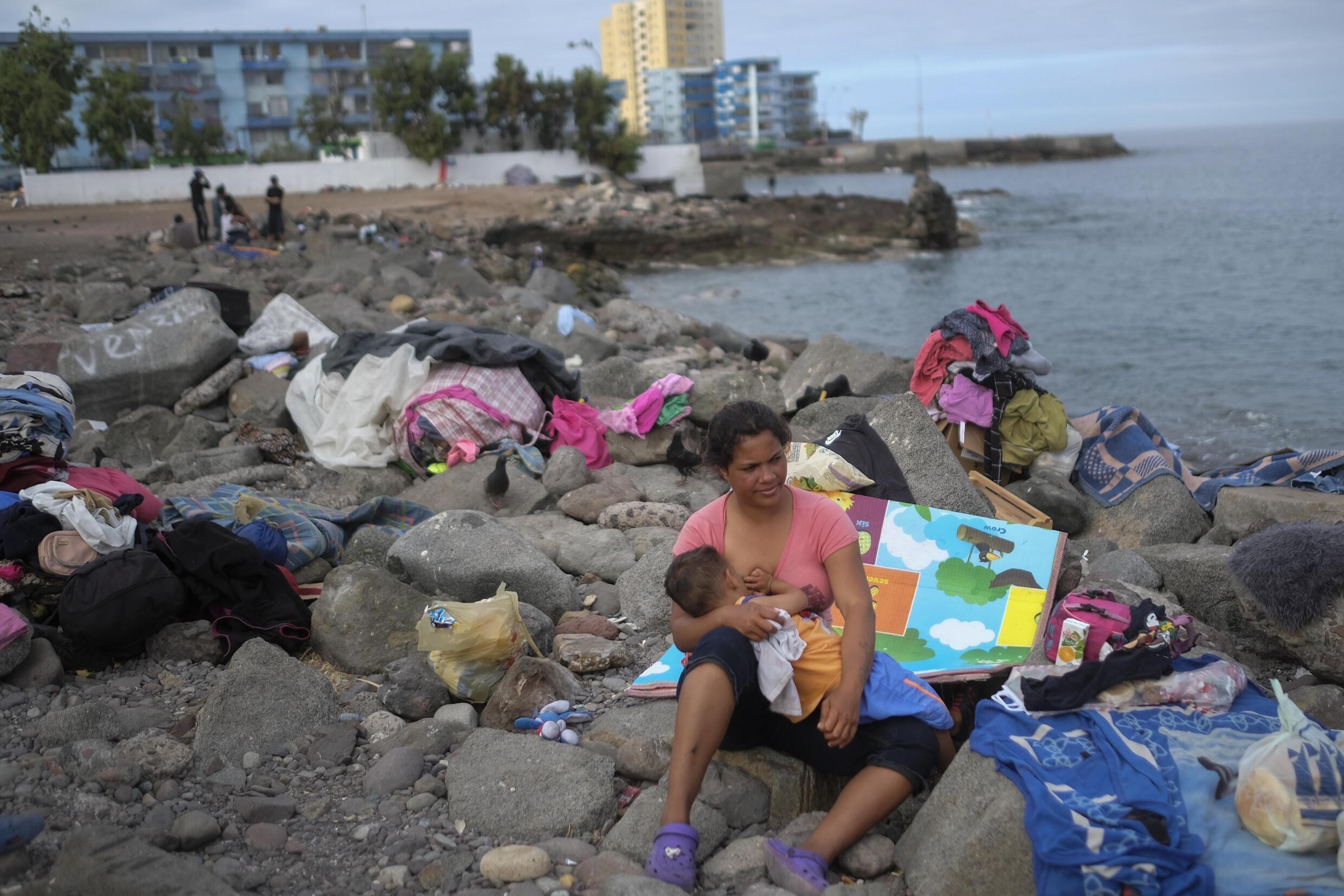 Una migrante venezolana amamanta a su hijo después de que la policía les dijera que levantaran el campamento a la orilla del mar donde vive con su familia en El Morro, un barrio de Iquique, Chile, el domingo 12 de diciembre de 2021.