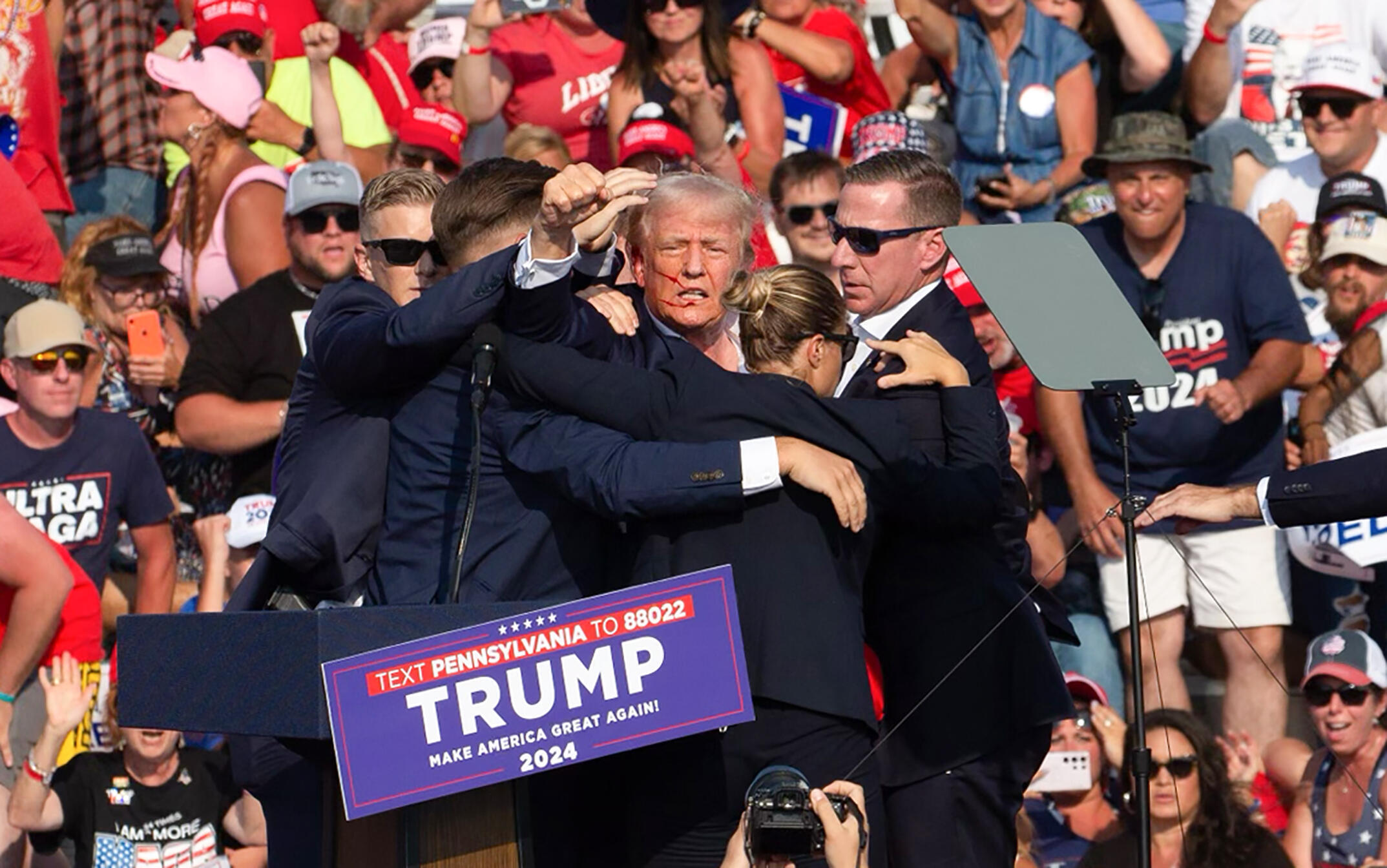 L'ancien président américain Donald Trump, blessé à l'oreille, lève le poing au moment d'être évacué de son meeting de campagne à Butler, le 13 juillet 2024 en Pennsylvanie