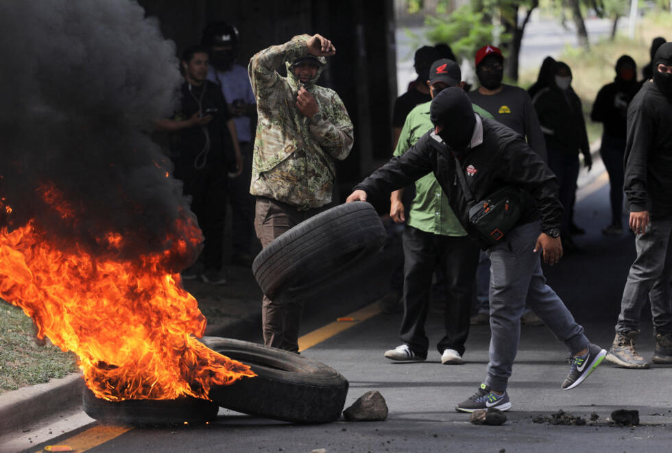 Archivo: un manifestante lleva una llanta para colocarla sobre una barricada en llamas como parte de una protesta casi dos semanas después de las elecciones presidenciales, mientras la votación sigue estancada en medio de papeletas sin contabilizar, acusaciones de fraude y fallas del sistema electoral, en Tegucigalpa, Honduras, el 15 de diciembre de 2025.