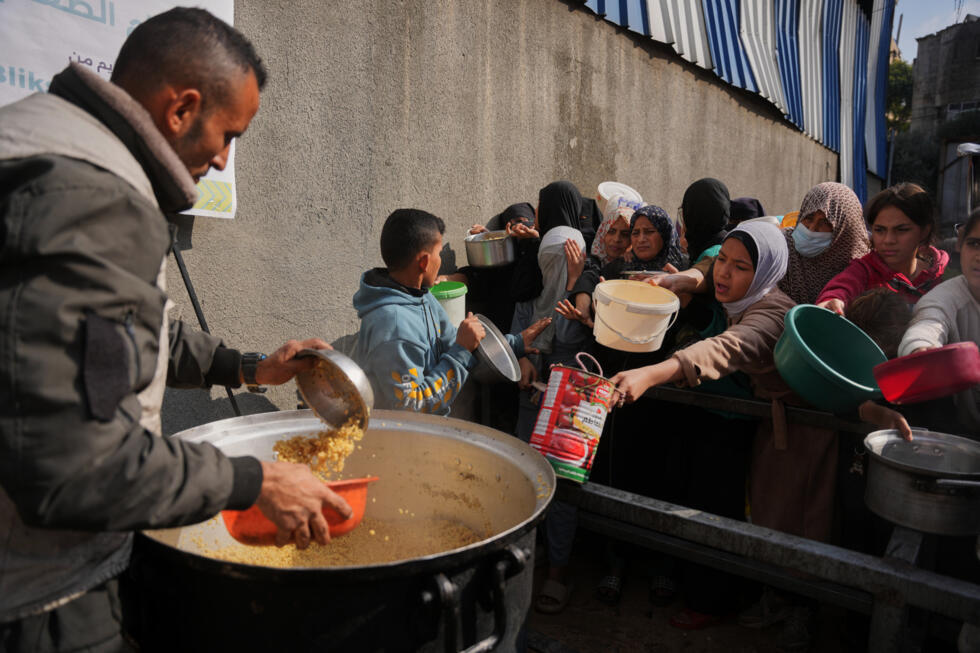 Palestinian women receive donated food at a community kitchen in Nuseirat, central Gaza Strip.