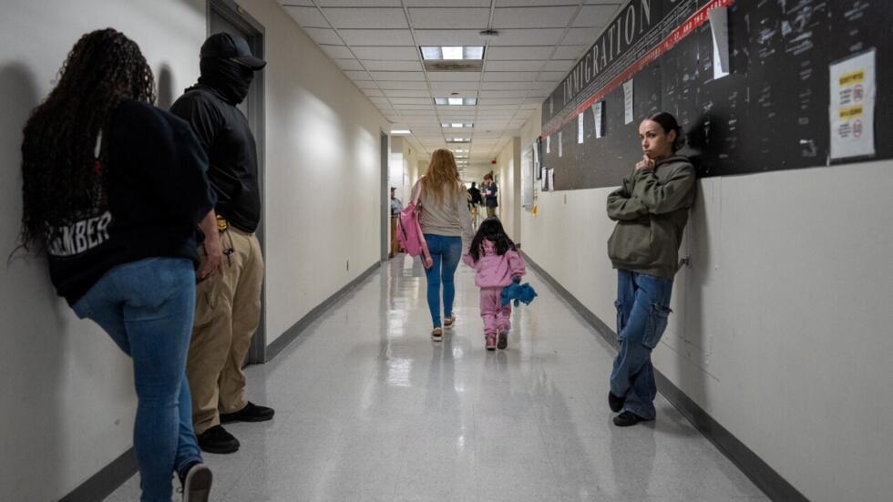 Un migrante camina por un pasillo con un niño mientras los oficiales federales de inmigración esperan para realizar detenciones en el tribunal de inmigración de Estados Unidos en Manhattan, en la ciudad de Nueva York, EE. UU., el 28 de agosto de 2025.