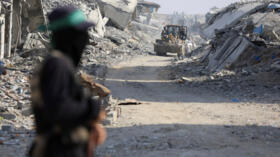 Machinery operates as a Palestinian Hamas militant stands guard near the so-called "yellow line" to which Israeli troops withdrew under the ceasefire agreement in Gaza City on November 2, 2025.