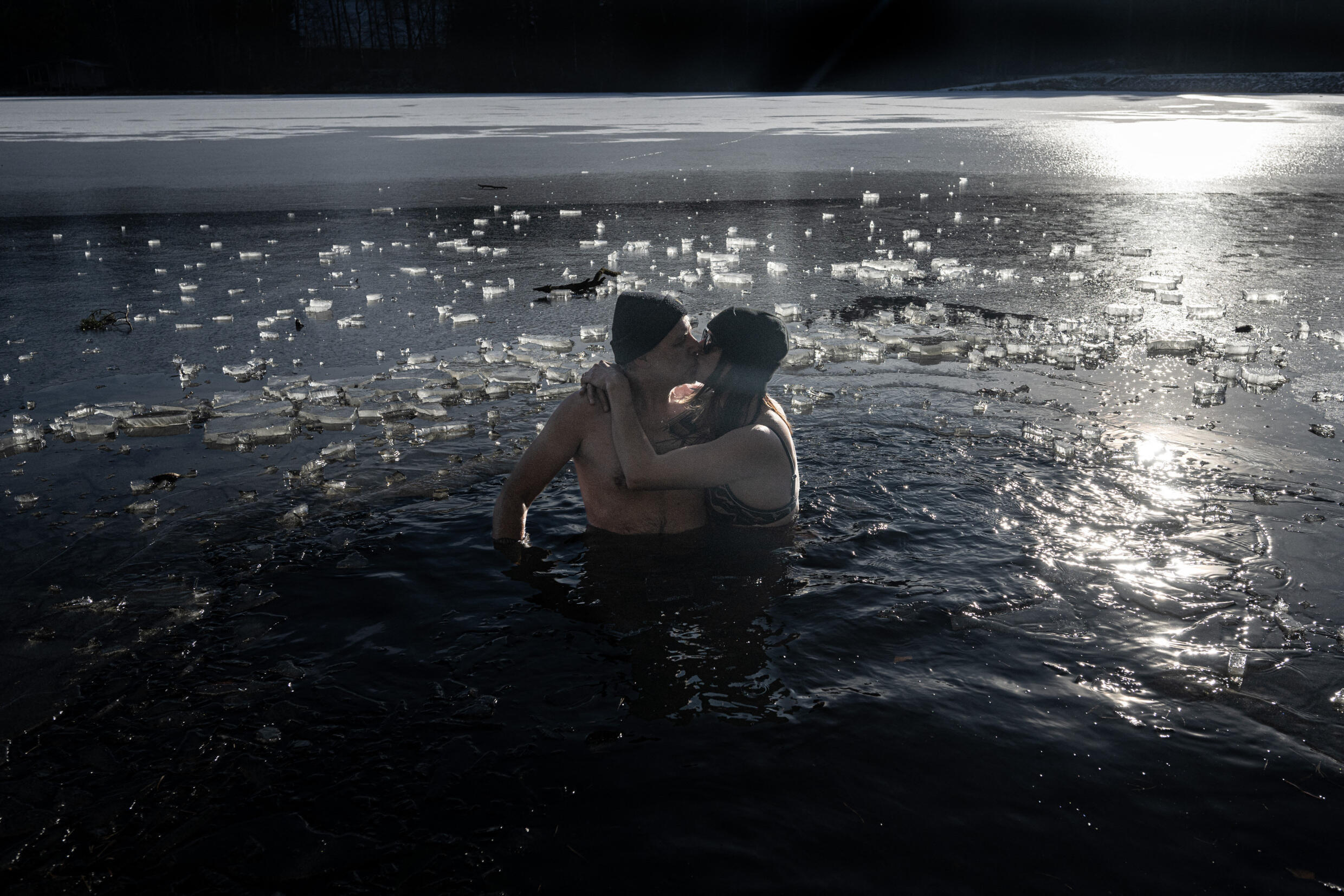 Un couple s'embrasse dans l'eau glacée de l'étang Kristanov lors du bain traditionnel du Nouvel An, le 1er janvier 2025, près de la ville de Prachatice, dans les montagnes de Sumava, en République tch