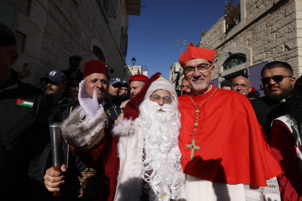 Le patriarche latin de Jérusalem, le cardinal Pierbattista Pizzaballa, pose pour une photo avec un homme habillé en Père Noël avant son arrivée à l'église de la Nativité, à Bethléem, en Cisjordanie oc
