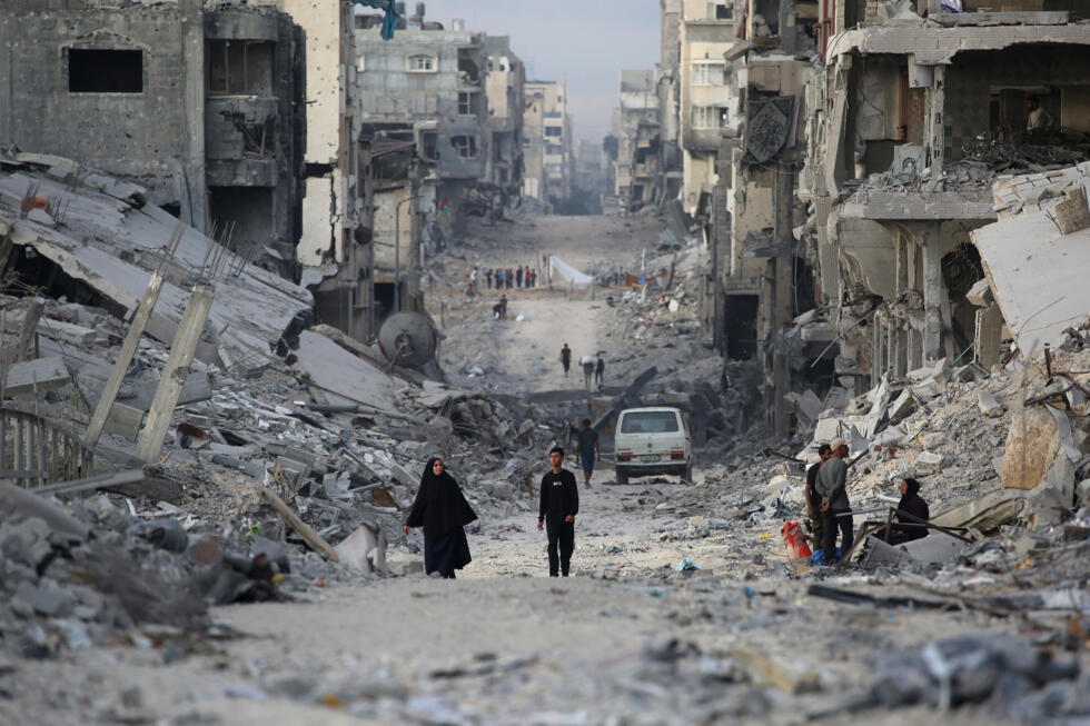 Des Palestiniens marchent au milieu de bâtiments détruits dans la ville de Gaza, le 12 octobre 2025, au troisième jour d'un cessez-le-feu entre Israël et le Hamas palestinien