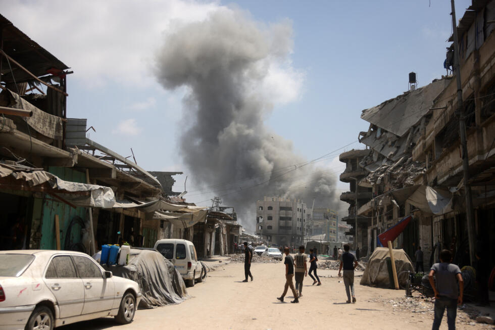 Palestinian watch as a plume of smoke rises during an Israeli strike on Gaza City's southern al-Zeitoun neighbourhood on August 8, 2025.