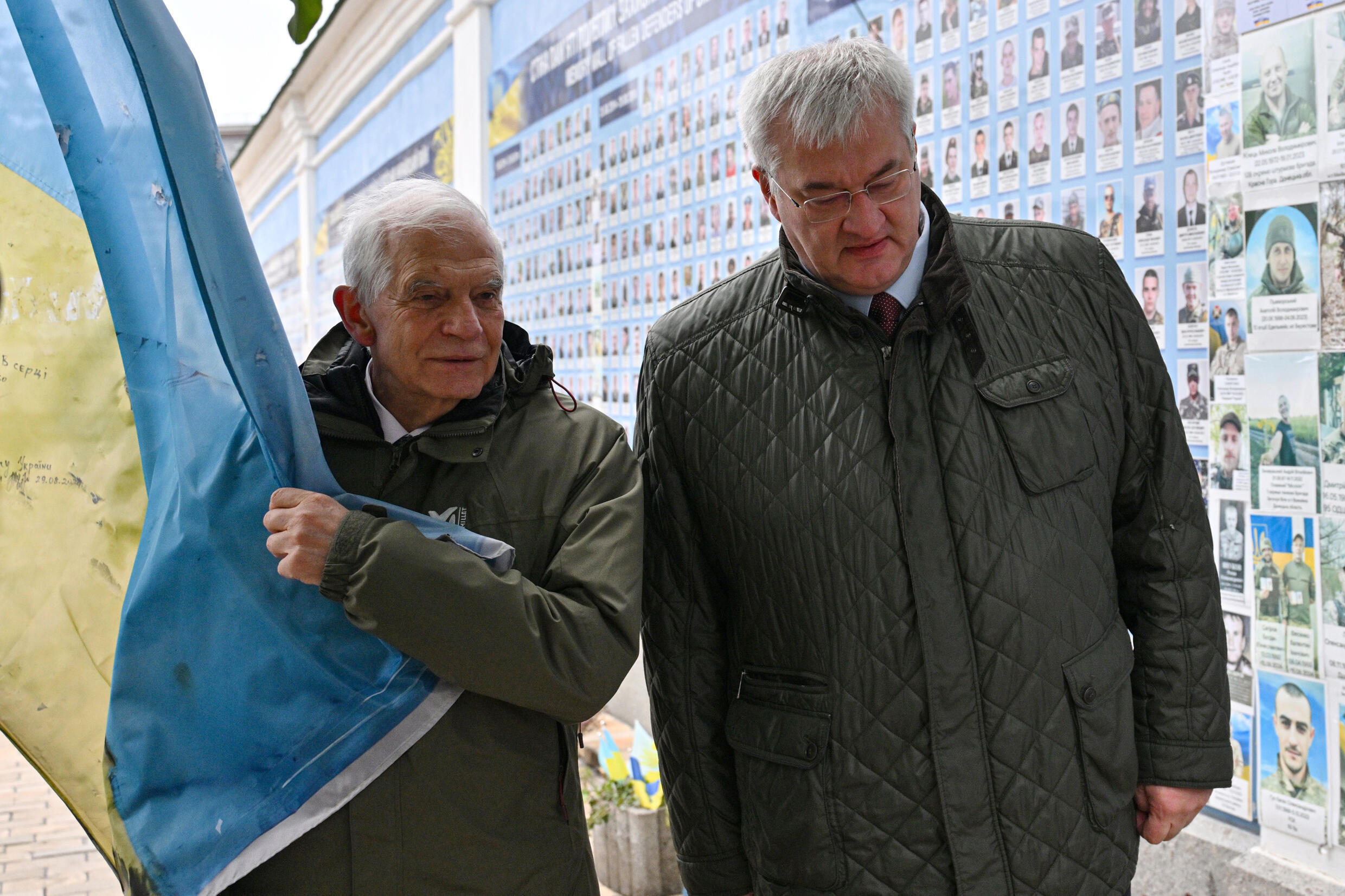 Le chef de la diplomatie européenne Josep Borrell (gauche) et son homologue ukrainien Andriï Sybiga marchent près d'un mur rassemblant les noms de soldats ukrainiens morts, le 9 novembre 2024 à Kiev