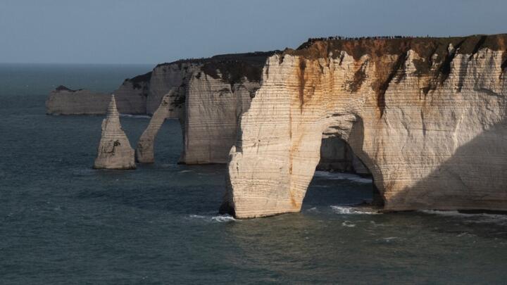 Visitors stand atop the Étretat cliffs in Normandy on November 7, 2021. 