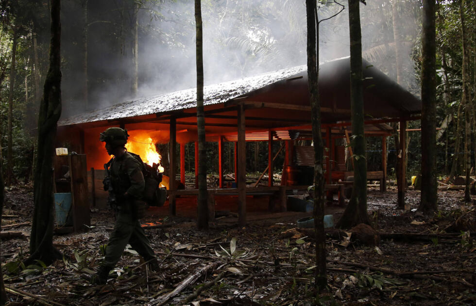 Imagen de archivo. Un agente de la policía antinarcóticos camina frente a un laboratorio de cocaína en llamas en Calamar, departamento del Guaviare, Colombia, el martes 2 de agosto de 2016.