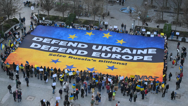 Demonstrators display a giant banner in the colours of the Ukrainian flag in Brussels on the eve of an EU summit.
