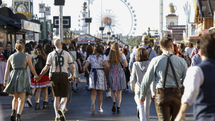 Visitors wearing traditional clothes walk at the Theresienwiese fair grounds for the opening of the 190th Oktoberfest beer festival in Munich, southern Germany on September 20, 2025. 