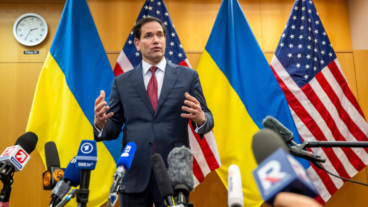 US Secretary of State Marco Rubio talks to the press at the US Mission to International Organizations in Geneva, Switzerland, against a backdrop of US and Ukrainian flags.