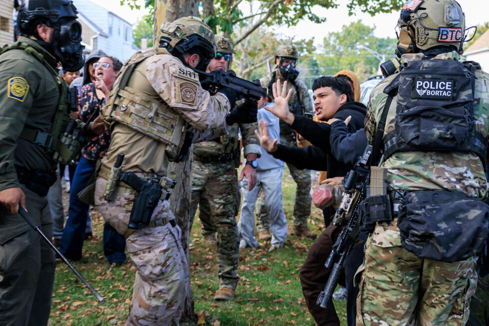 A law enforcement officer points a crowd control weapon at a protester in Chicago, October 14, 2025.