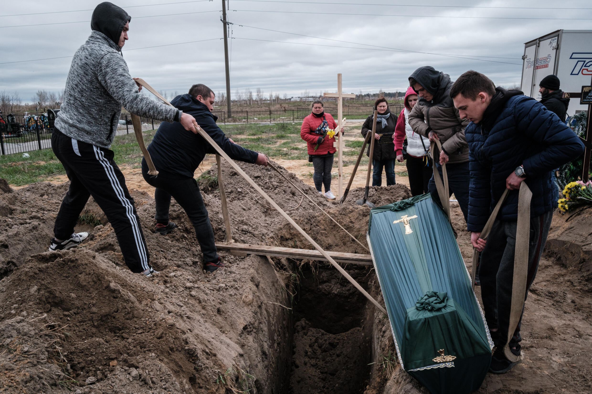 Oleksandr Smagliuk, left, helps to bury his relative Mykhailo Romaniuk, who was shot dead while riding a bicycle in the Kyiv suburb of Bucha in March
