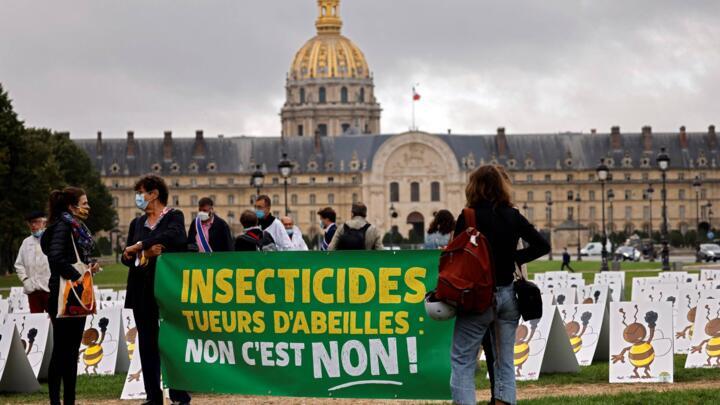 Beekeepers hold a placard reading "bee-killing insecticides no it's no" gather for a demonstration to protest against a controversial bill allowing the reintroduction of seeds coated with neonicotinoi