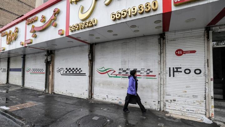 A woman walks past a row of closed shops on Satarkhan street in Tehran, Iran, Monday, December 5, 2022.