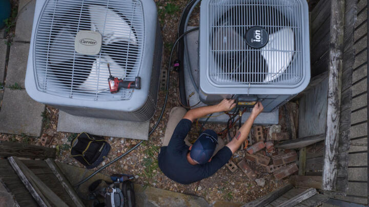A technician tests the refrigerant levels in an air conditioning unit during a heatwave in Houston, Texas, US, on August 24, 2023. 