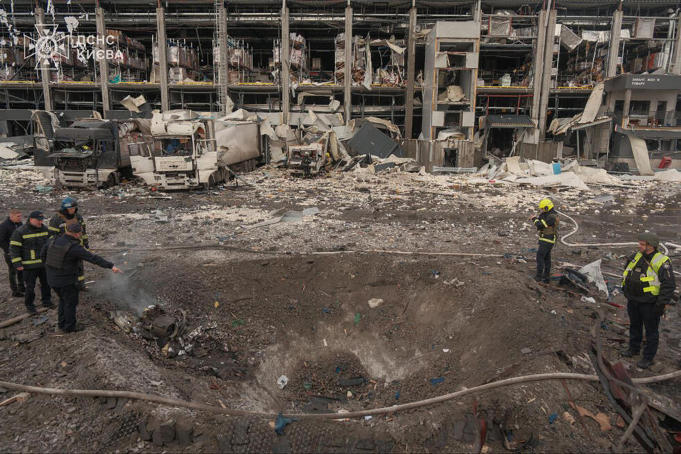 Ukrainian law enforcement officers inspect a crater at the site of an air attack in Kyiv.