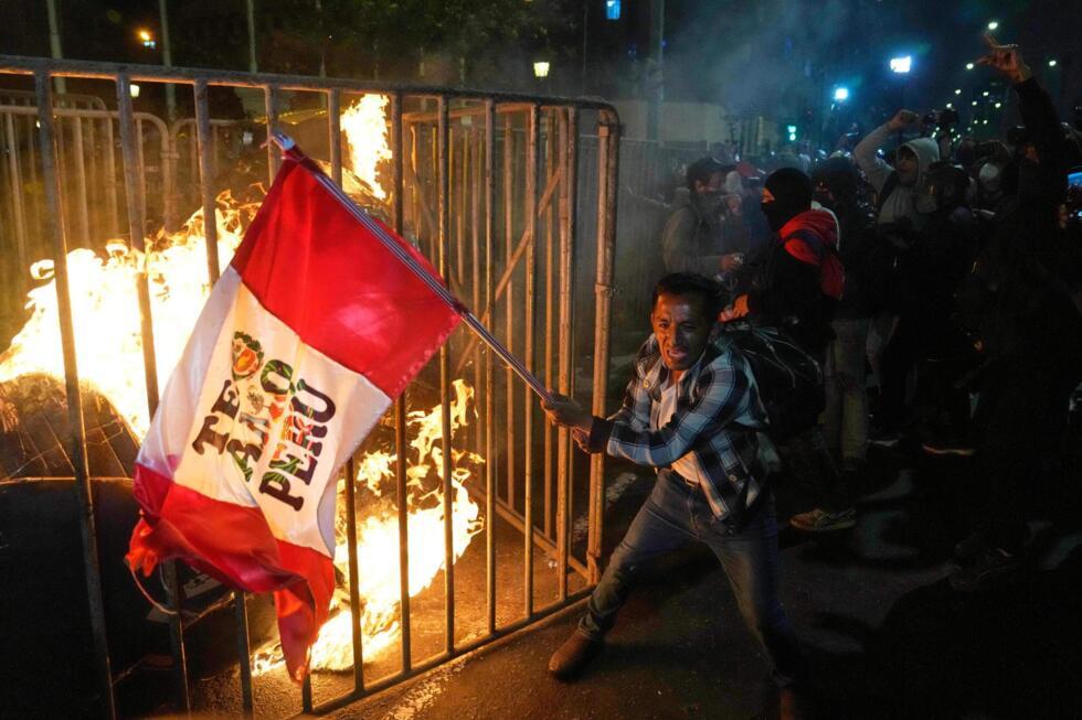 A demonstrator waves a Peruvian flag as a cardboard doll burns in front of Congress in Lima, Peru, Wednesday on October 15, 2025.