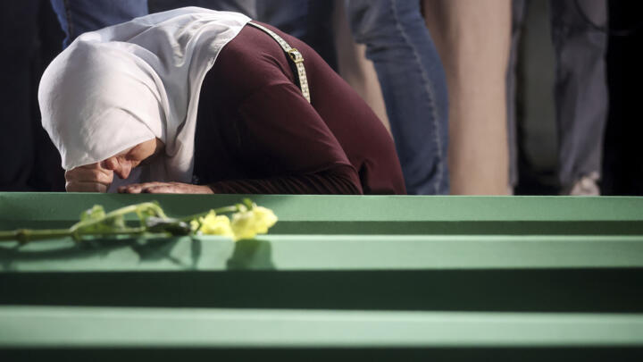 A woman mourns next to a coffin, containing remains of her relative, a newly identified victim of the Srebrenica genocide, in Potocari, Bosnia on July 9, 2025.