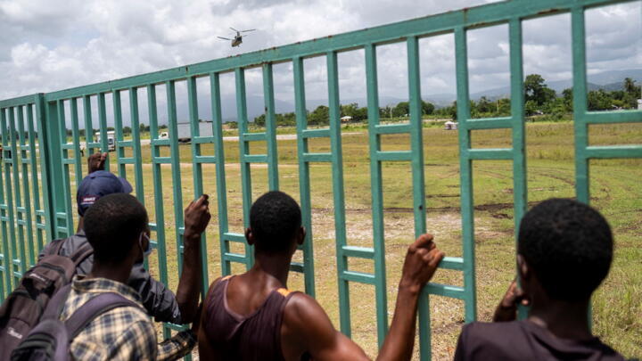 People watch a military helicopter taking off after it delivered food and supplies at the airport after Saturday's 7.2 magnitude quake, in Les Cayes, Haiti, August 18, 2021.